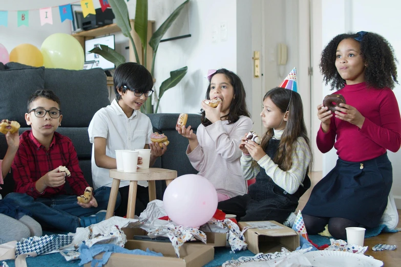 a group of children sitting on the floor eating food, a cartoon, by Emma Andijewska, pexels contest winner, party balloons, [ cinematic, eating a donut, cardboard
