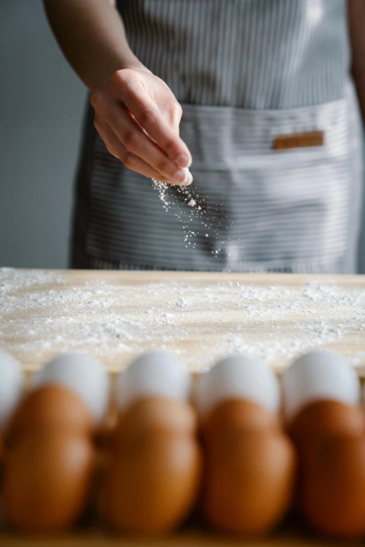 a woman in an apron sprinkles salt on eggs, a portrait, inspired by Gordon Browne, trending on pexels, detail shot, paul barson, tabletop, white