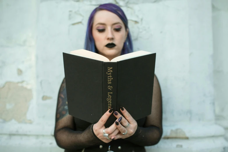 a woman with purple hair is reading a book, an album cover, by Matt Cavotta, pexels contest winner, aestheticism, gold and black metal, matte black paper, full-figure, pagans