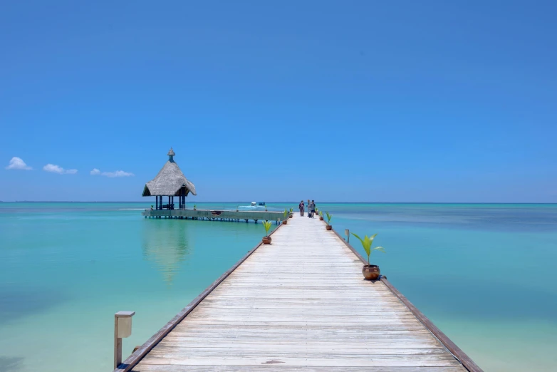 a pier in the middle of a body of water, sumatraism, clear blue skies, white beaches, colombia, slide show