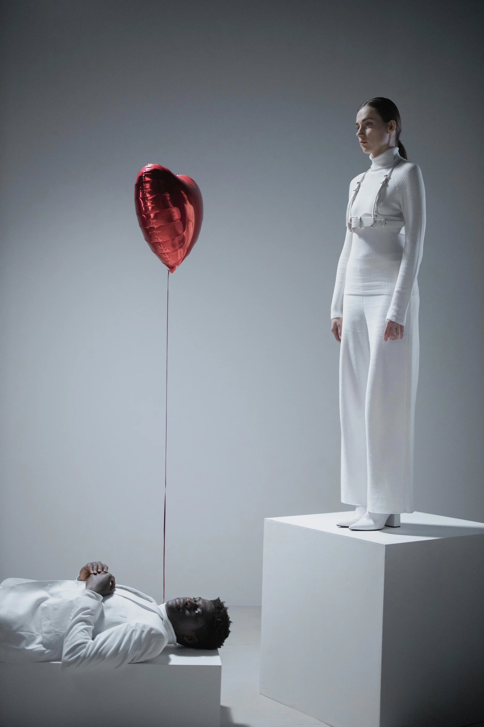 a woman standing on top of a bed next to a heart shaped balloon, a surrealist sculpture, inspired by Marina Abramović, photograph of a techwear woman, all white render, archviz, metal garments