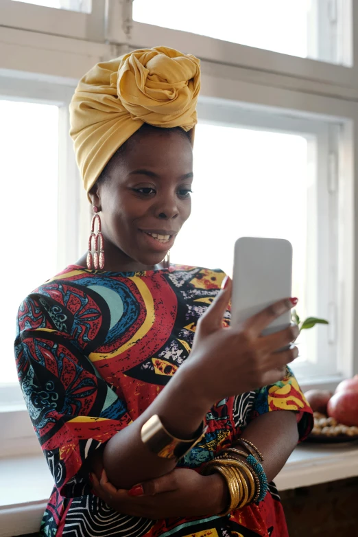 a woman wearing a turban looking at her phone, afrofuturism, at home, 2019 trending photo, lgbtq, wearing an african dress