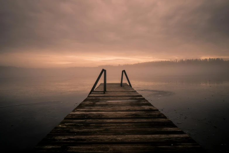 a dock in the middle of a body of water, by Holger Roed, pexels contest winner, romanticism, brown mist, espoo, looking onto the horizon, faded pink