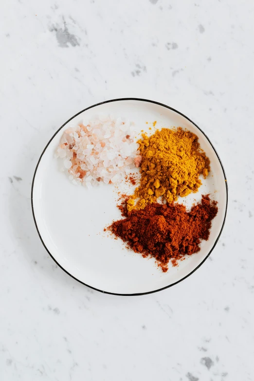 a white plate topped with different colored spices, by Carey Morris, red+yellow colours, scales with magic powder, jen atkin, ground broken