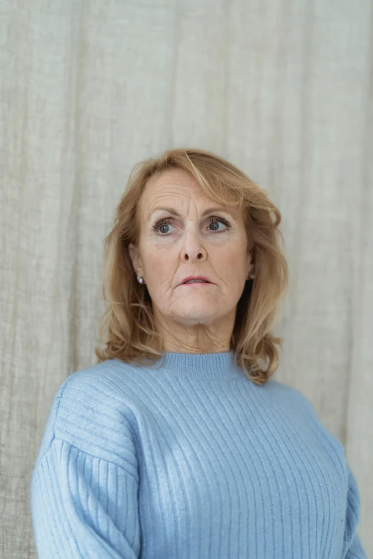 a woman in a blue sweater posing for a picture, inspired by Cornelia Parker, trending on pexels, hyperrealism, scowling, 50 years old, scandinavian, judy chicago