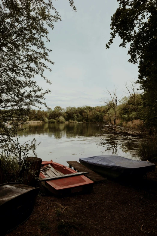 a couple of boats sitting on top of a lake, on a riverbank, cosy atmoshpere, ede laszlo, high-quality photo