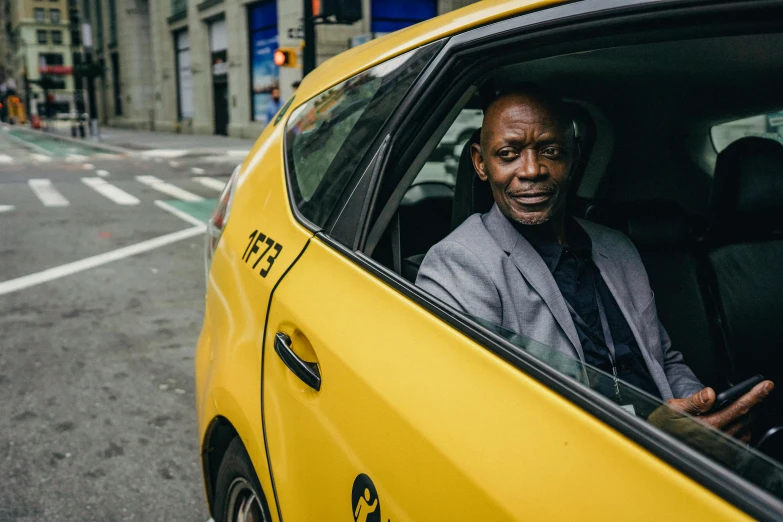 a man sitting in the driver's seat of a taxi, a photo, by Daniel Gelon, lance reddick, promotional image, colour portrait photograph, on a yellow canva