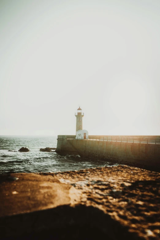 a light house sitting on top of a pier next to the ocean, a picture, pexels contest winner, paul barson, low quality photo, medium format. soft light, back - lit