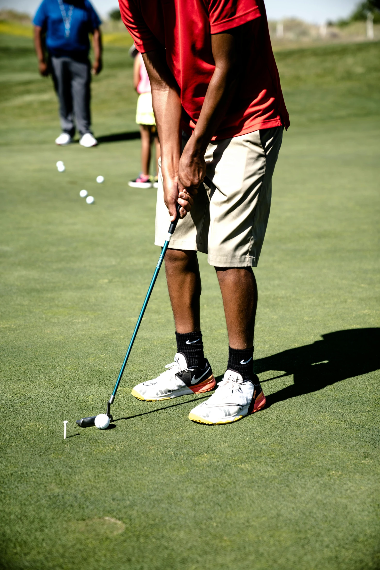 a man taking a swing at a golf ball, by Everett Warner, pexels, wearing red shorts, school class, off - putting, dark-skinned