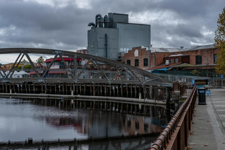 a bridge over a body of water with buildings in the background, a portrait, inspired by Thomas Struth, unsplash, steel mill, espoo, paisley, thumbnail