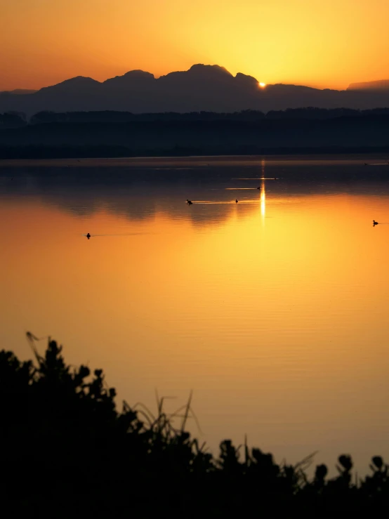 the sun is setting over a body of water, by Jan Tengnagel, pexels contest winner, romanticism, distant mountains, gold refractions off water, telephoto, today\'s featured photograph 4k