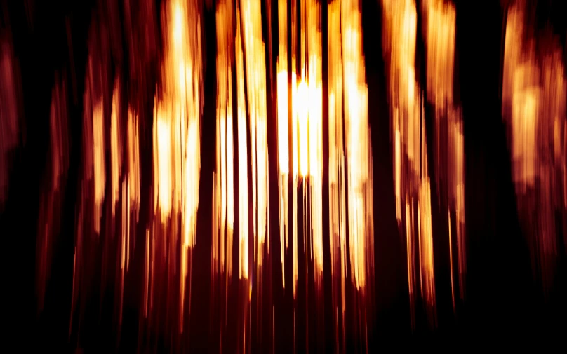 a blurry photo of a forest at night, a digital rendering, by Jan Rustem, unsplash, lyrical abstraction, gold and red metal, vertical lines, dripping candles, intense sunlight