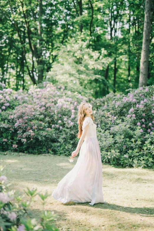 a woman in a white dress walking through a field, inspired by Oleg Oprisco, unsplash, romanticism, lilacs, in serene forest setting, 15081959 21121991 01012000 4k, wedding