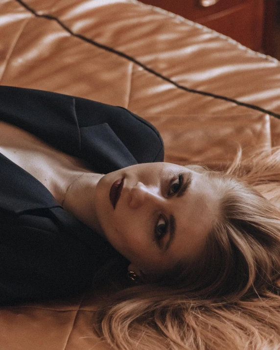 a beautiful woman laying on top of a bed, an album cover, inspired by Elsa Bleda, trending on pexels, renaissance, wearing black suit, britt marling style, non binary model, she wears a jacket