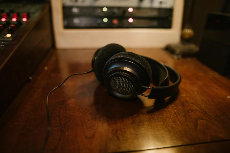 a pair of headphones sitting on top of a wooden table, trending on pexels, hyperrealism, black and gold wires, thumbnail, low quality photo, 90s photo