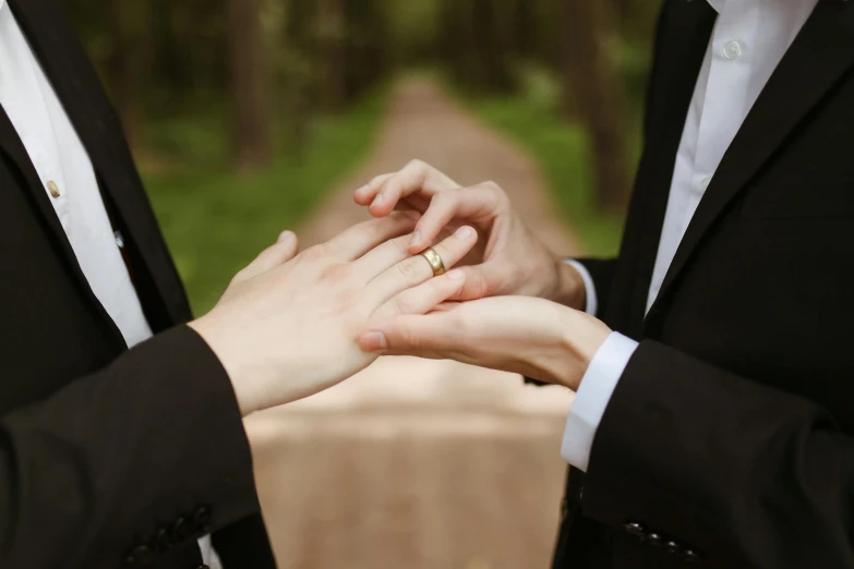 a close up of a person putting a ring on another person's finger, an album cover, unsplash, romanticism, wearing a tuxedo, woodlands, full colour, al fresco