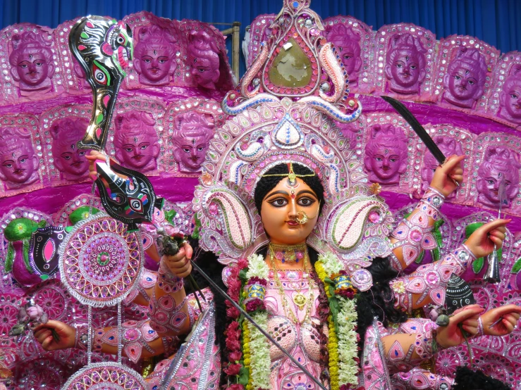 a close up of a statue of a woman, samikshavad, ornate mask and fabrics, pink, she is holding a long staff, confetti
