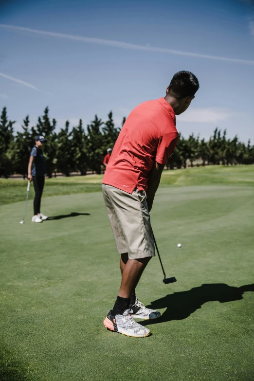 a man taking a swing at a golf ball, unsplash, happening, wearing red shorts, off - putting, asian man, person in foreground