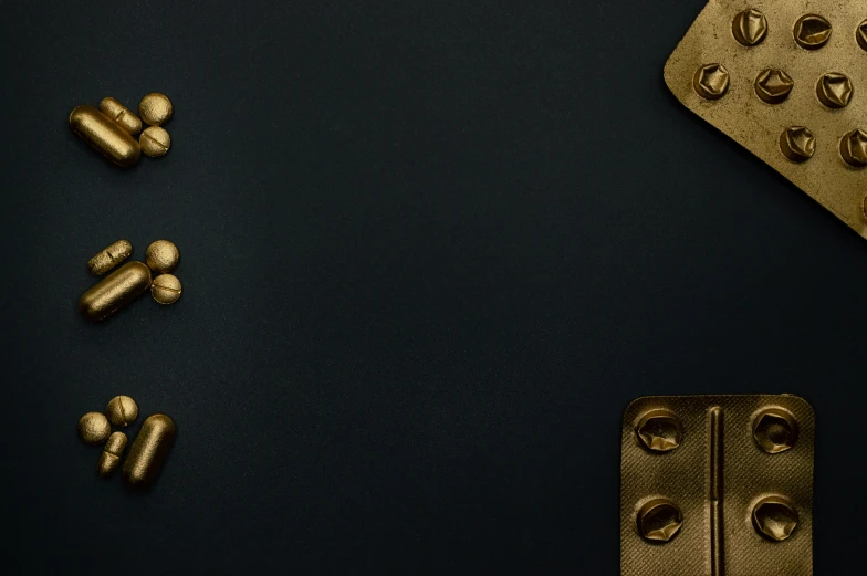 a bunch of pills sitting on top of a table, an album cover, inspired by George Ault, trending on unsplash, visual art, metallic brass accessories, colors with gold and dark blue, rivets, detailed product image