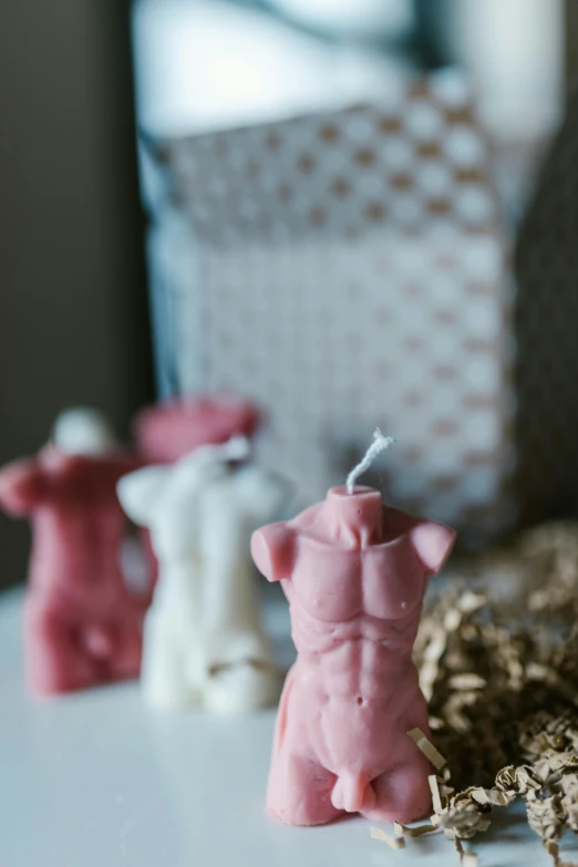 a couple of figurines sitting on top of a table, waxy candles, focus on torso, pink clothes, upcycled