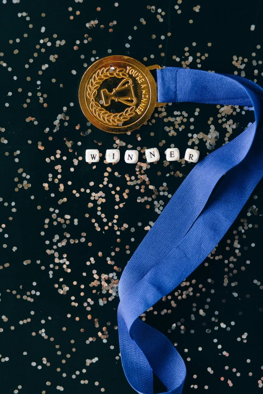 a gold medal sitting on top of a blue ribbon, by Julia Pishtar, pexels contest winner, renaissance, yearbook photo, sequins, detailed letters, (night)