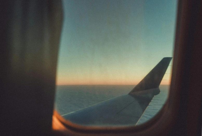 a view of the wing of an airplane from a window, a polaroid photo, by Elsa Bleda, pexels contest winner, postminimalism, gazing off into the horizon, shades of aerochrome, early evening, oceanside