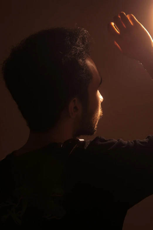 a man holding a light up in the dark, inspired by casey baugh, pexels contest winner, hair light, volumetric backlighting, still from a music video, profile shot