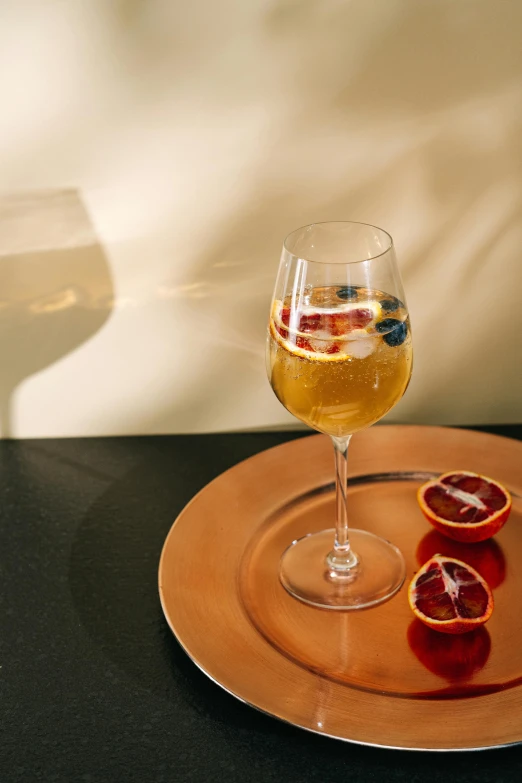 a glass of wine and some blood oranges on a plate, inspired by Carlo Martini, pexels contest winner, renaissance, tall iced tea glass, red blue and gold color scheme, a blond, 2030s