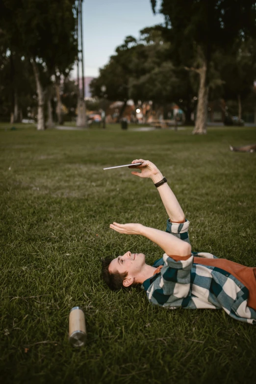 a man laying in the grass with a frisbee, unsplash, realism, checking her cell phone, 3 5 mm pointing up, in a square, very long arms