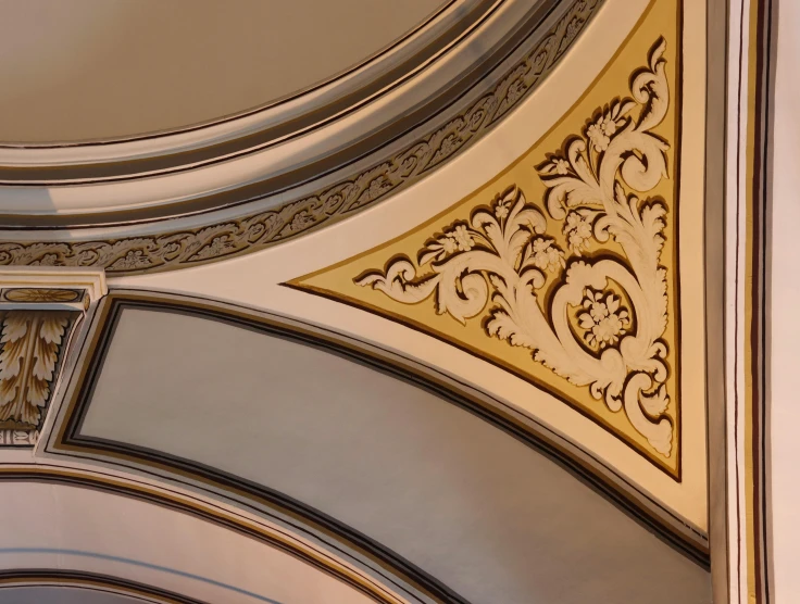 a clock mounted to the ceiling of a building, a detailed painting, inspired by Sydney Prior Hall, trending on unsplash, art nouveau, curving geometric arches, silver with gold trim, medium closeup shot, highly detailed gold filigree