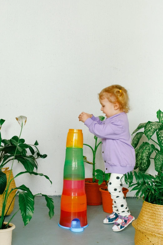 a little girl that is playing with a tower, pexels contest winner, big interior plants, green and purple, multi - coloured, sustainability