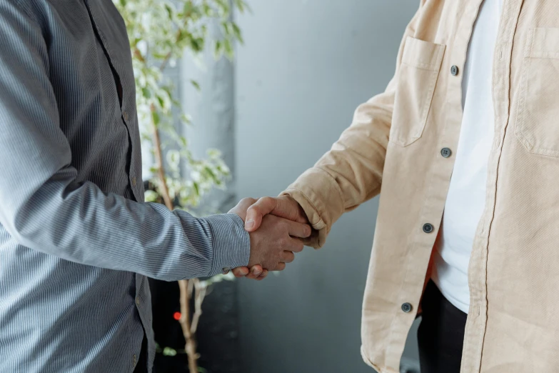 two men shaking hands in front of a plant, pexels contest winner, office clothes, background image, wearing jacket, ignant