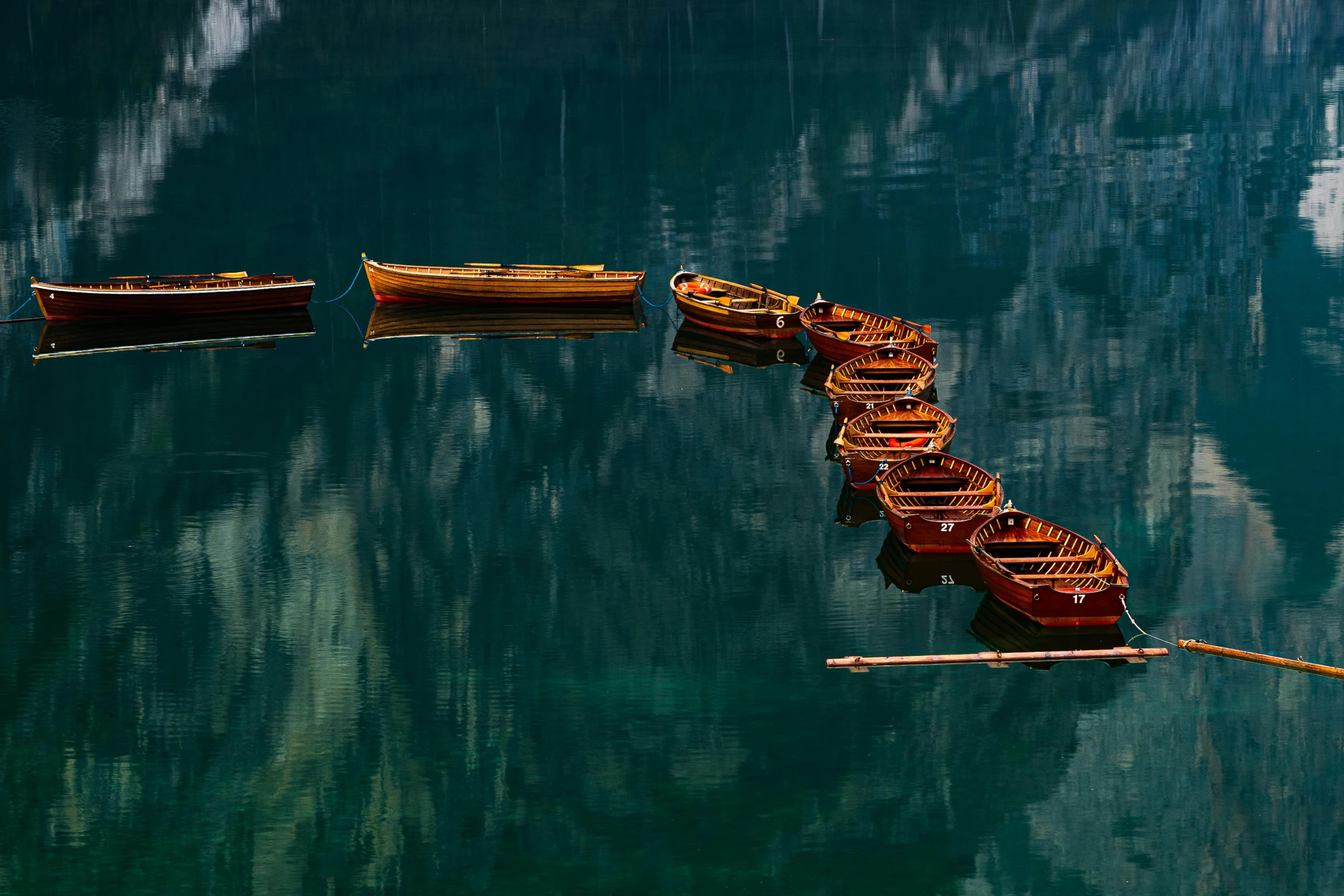a group of boats floating on top of a lake, by Jan Rustem, pexels contest winner, minimalism, dark green water, switzerland, floating chinese lampoons, reflections in copper
