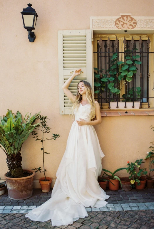 a woman in a wedding dress standing in front of a window, by Sara Saftleven, running through italian town, in garden, flowy golden hair, photoshoot for skincare brand