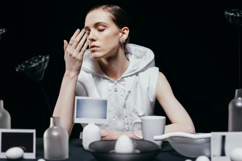 a woman sitting at a table with her hands on her face, trending on unsplash, hyperrealism, off-white plated armor, breakfast, fashion week backstage, moonlight