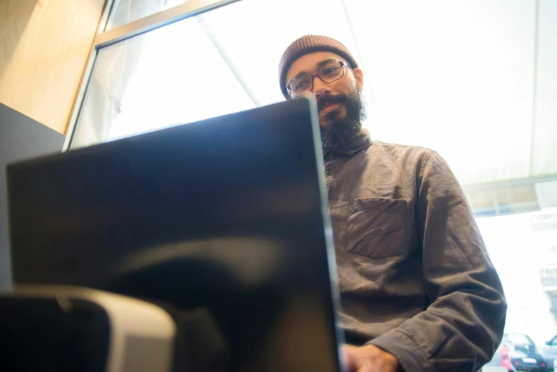 a man sitting in front of a laptop computer, by Jessie Algie, unsplash, bearded, 2 5 6 x 2 5 6 pixels, bottom angle, reflecting