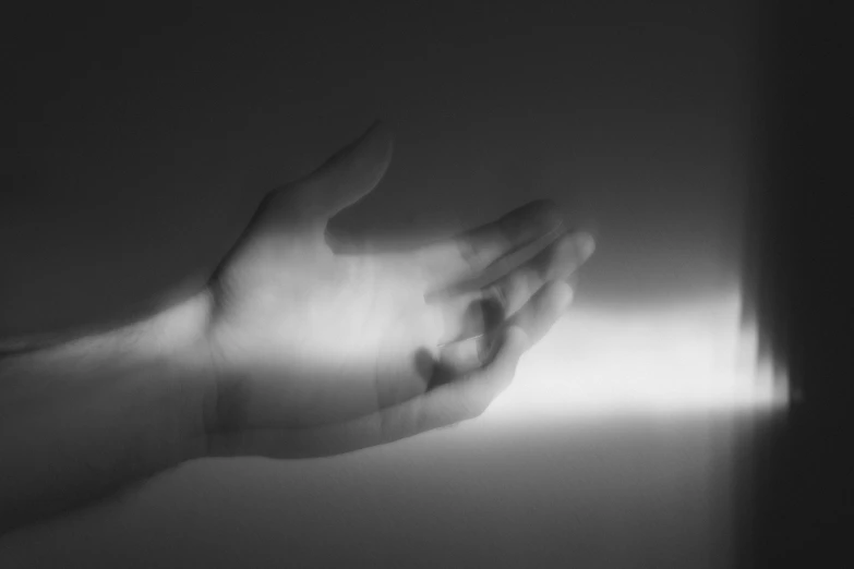 a black and white photo of a person's hand, light and space, light simulation, partially cupping her hands, dreamlike light incidence, julia sarda