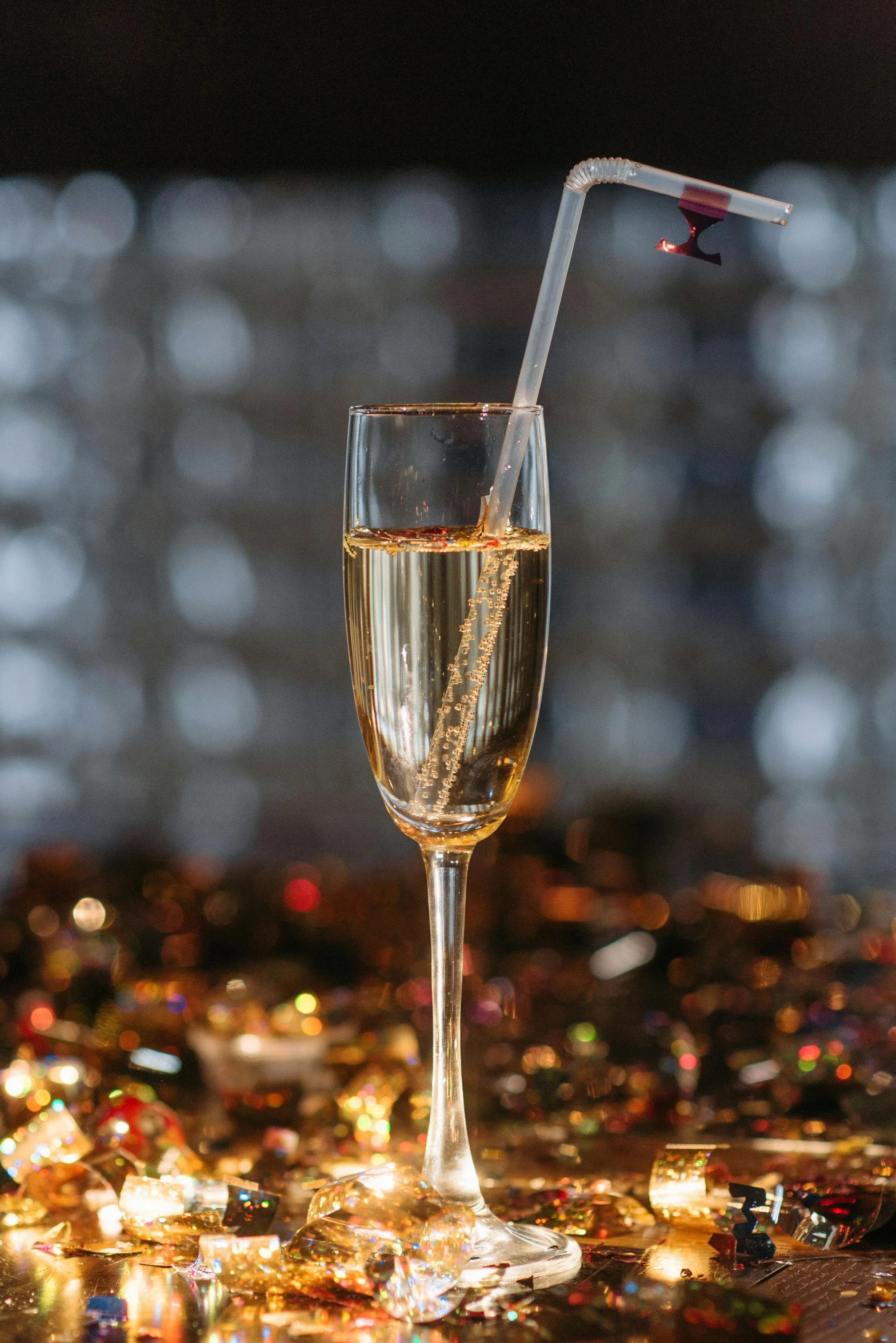 a glass of champagne sitting on top of a table, holding wand, with sparking circuits, with a straw, a long-shot