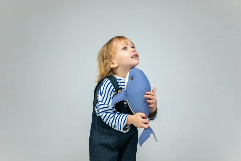 a little girl that is holding a pillow, unsplash, plesiosaur, blue overalls, side profile view, boy