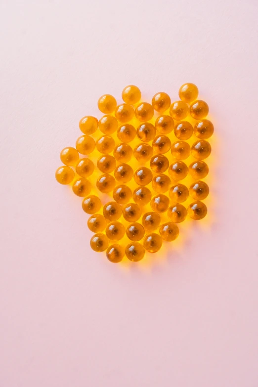 fish oil capsules on a pink background, by Carey Morris, made of honey, many floating spheres, 64x64, liquid translucent amber