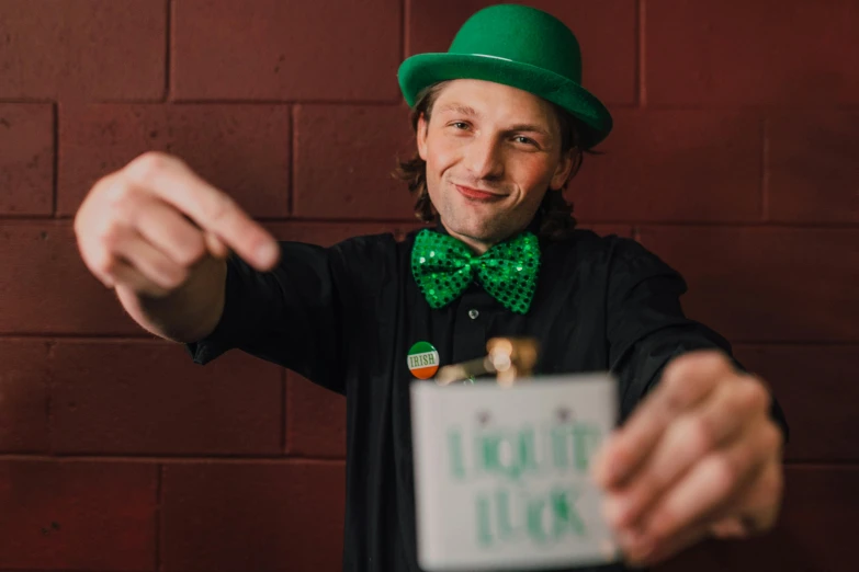 a man in a green hat and bow tie holding a sign, pexels contest winner, liquid magic, four leaf clover, avatar image, lachlan bailey