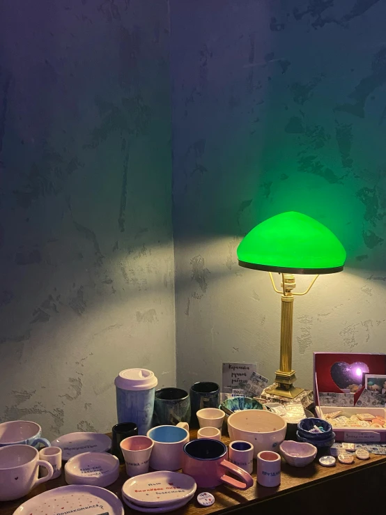 a green lamp sitting on top of a wooden table, chungking express color palette, snapchat photo, room of the nameless painter, made of glowing wax and ceramic