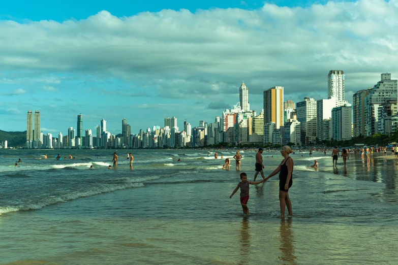 a group of people standing on top of a sandy beach, by Fernando Gerassi, pexels contest winner, city skyline, people swimming, helio oiticica, koyaanisqatsi