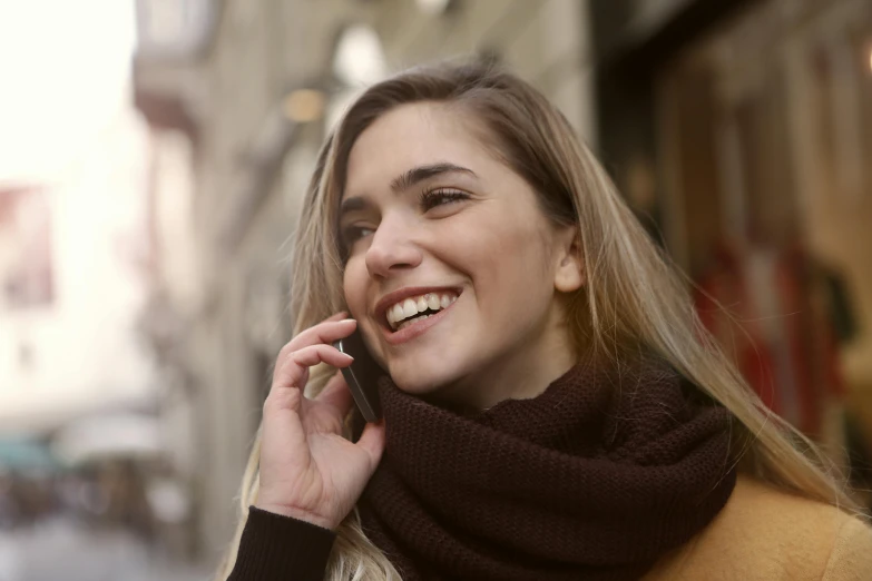 a woman smiling while talking on a cell phone, trending on pexels, italian looking emma, young blonde woman, brown, ƒ 1. 8