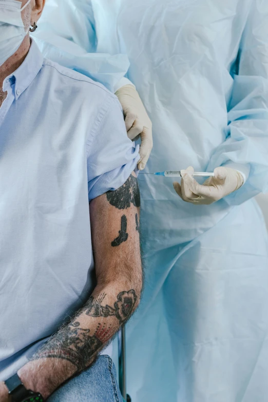 a man sitting in a chair with a tattoo on his arm, a tattoo, shutterstock, renaissance, surgical gown and scrubs on, syringe, zoomed in, two men hugging