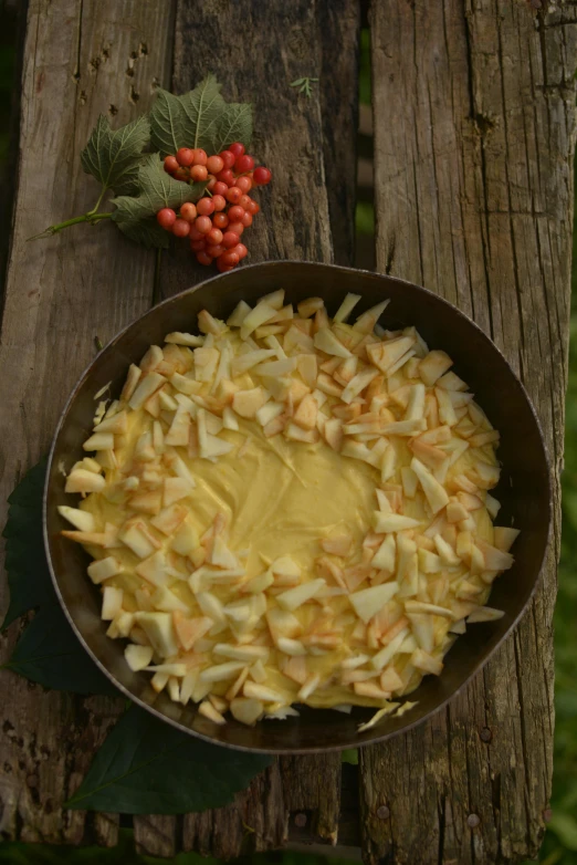 a pan of food sitting on top of a wooden table, inspired by Géza Dósa, hurufiyya, yellow apples, cream, canopee, petals