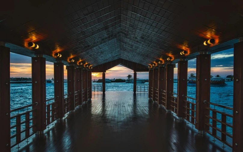 a walkway next to a body of water at sunset, visual art, wooden ceiling, during the night, symmetrical image