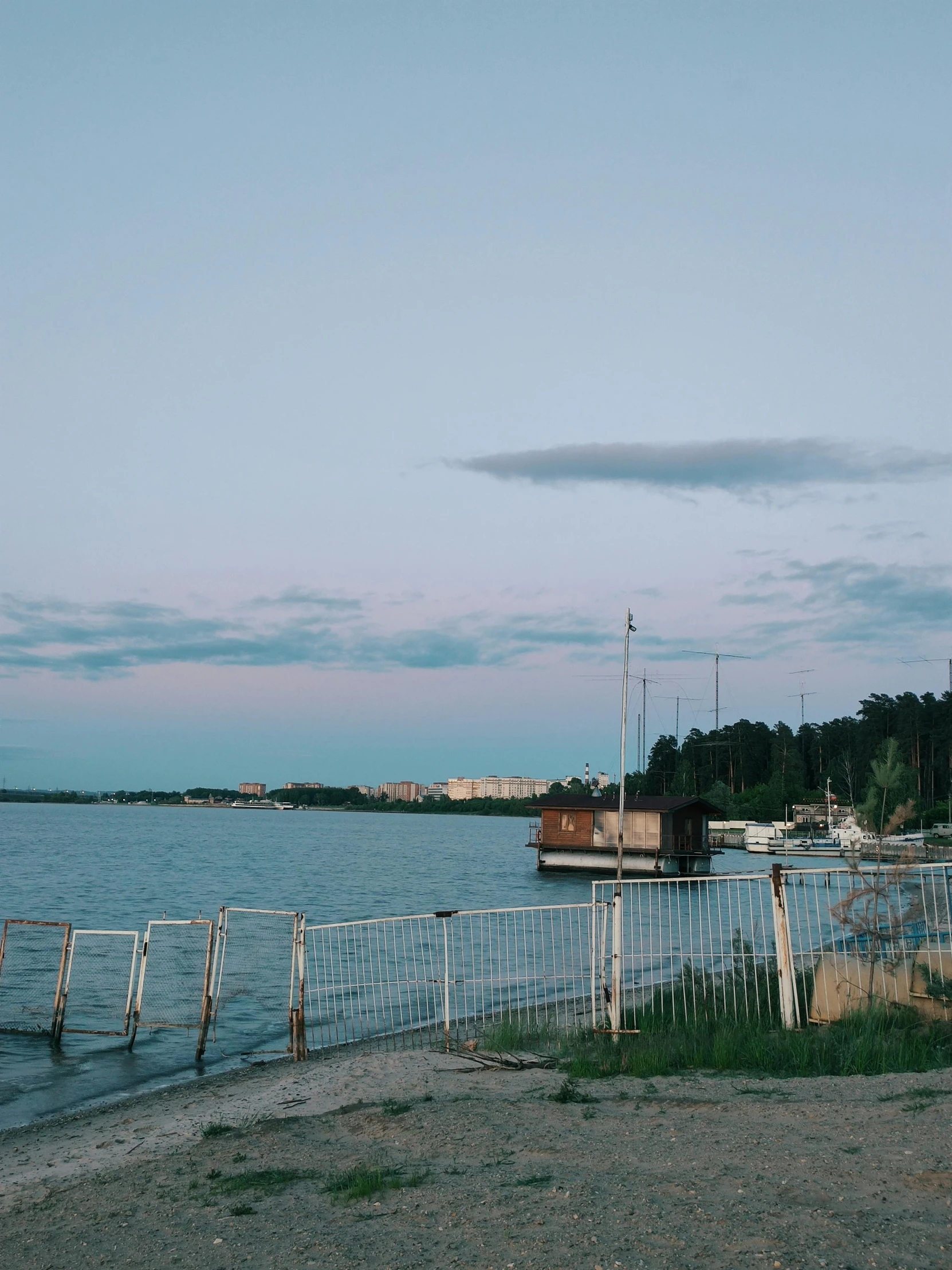 a body of water that is next to a fence, a picture, inspired by Wilhelm Marstrand, unsplash, happening, magical soviet town, at dusk!, today\'s featured photograph 4k, summer evening