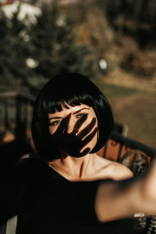 a woman taking a selfie with her phone, inspired by Elsa Bleda, pexels contest winner, surrealism, black bob haircut, faces covered in shadows, with bangs, sunbathed skin