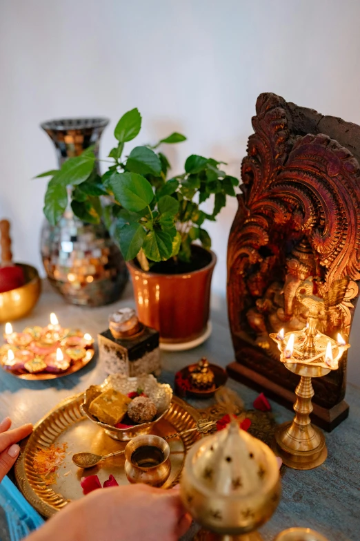 a person sitting at a table with a plate of food, a still life, hurufiyya, hindu ornaments, lush plants and lanterns, 2019 trending photo, on the altar